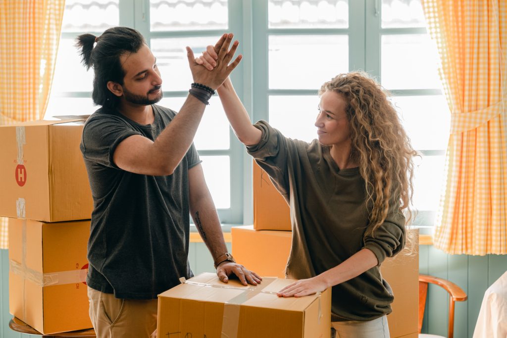 Multiracial couple giving high give standing near pile of boxes